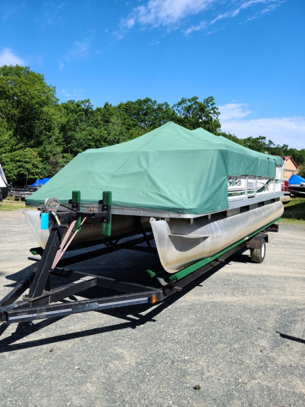 A boat with a cover on it is parked in the parking lot.