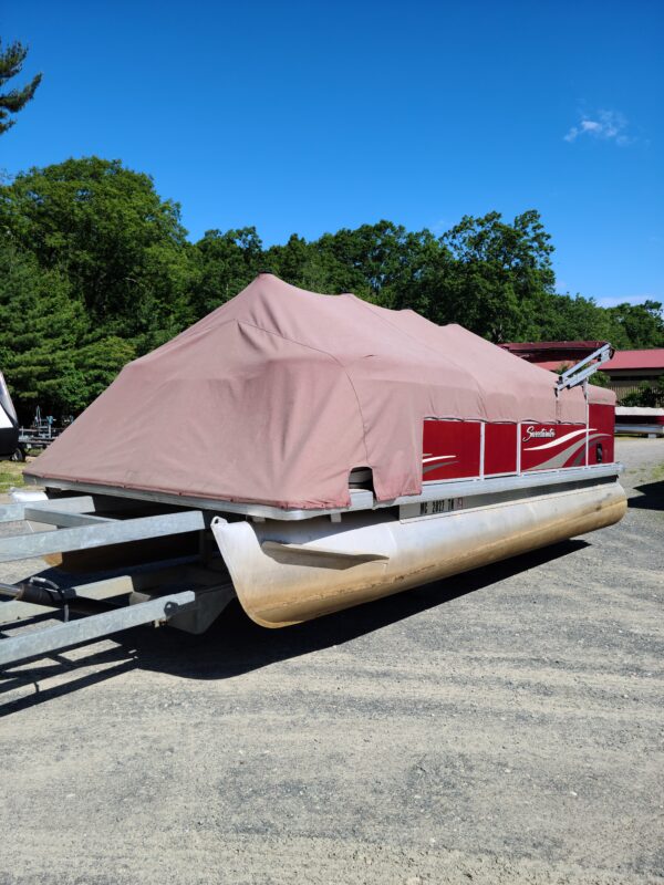 A boat with a cover on it parked in the parking lot.