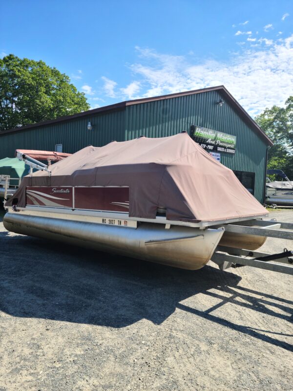 A boat is parked in the gravel near a building.